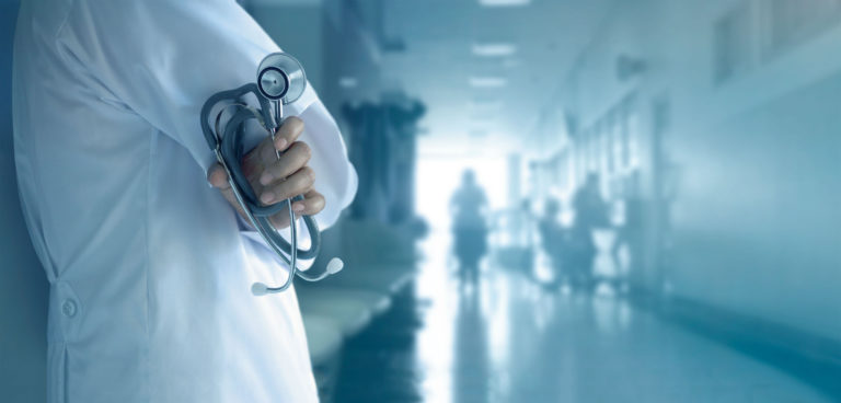 Doctor with stethoscope in hand on hospital background